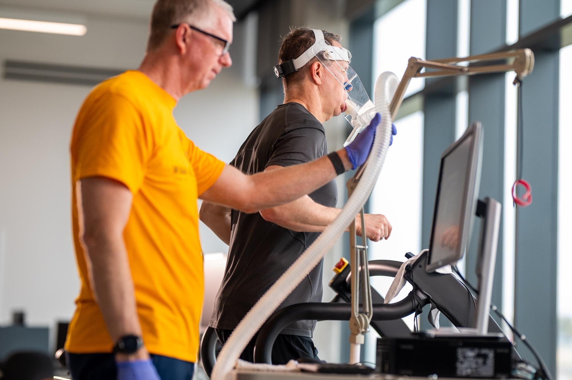 A researcher at East Texas A&M University monitors a participant running on a treadmill while wearing a respiratory mask for a human performance and movement study.